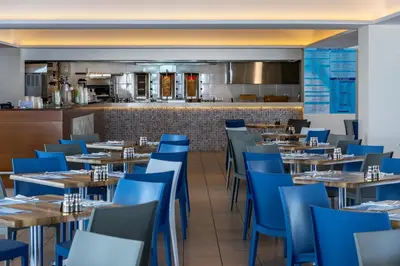 a restaurant with wooden tables and blue chairs at Tofinis Hotel in Ayia Napa