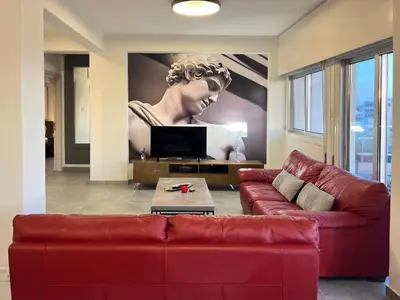 a living room with a red couch and a painting of a woman at River View Apartment in center Nicosia in Nicosia