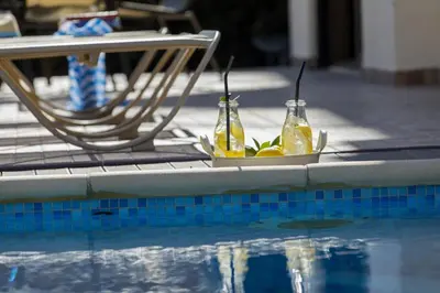 a swimming pool with two bottles of drinks and a chair at Protaras Fig Tree Bay Villa Buena in Protaras