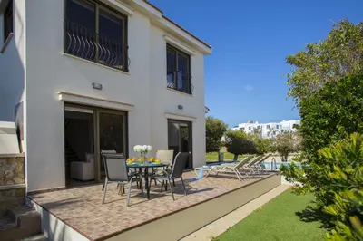 a patio with a table and chairs next to a building at Protaras Fig Tree Bay Villa Buena in Protaras