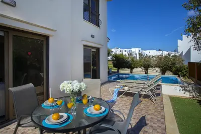 a table and chairs on a patio next to a pool at Protaras Fig Tree Bay Villa Buena in Protaras