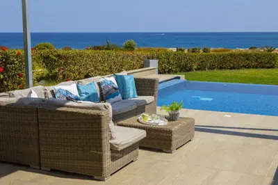 a patio with wicker furniture next to a swimming pool at Protaras Seafront Villa Infinte Aretousa in Protaras
