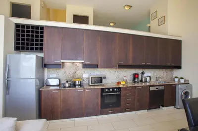 a kitchen with wooden cabinets and a stainless steel refrigerator at Protaras Seafront Villa Infinte Aretousa in Protaras