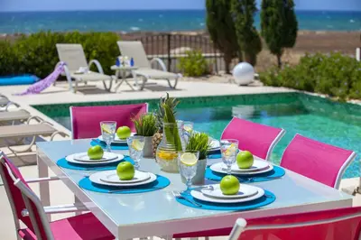 a table with plates of food next to a swimming pool at Ayia Thekla Seafront Villa Lavender in Ayia Napa