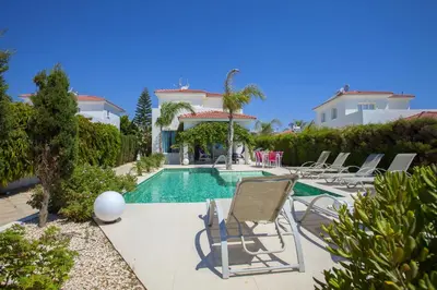 a villa with a swimming pool and lounge chairs at Ayia Thekla Seafront Villa Lavender in Ayia Napa