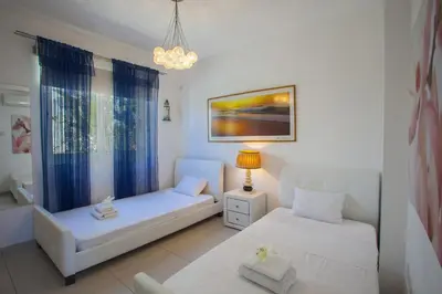a bedroom with two white beds and a chandelier at Ayia Thekla Seafront Villa Lavender in Ayia Napa