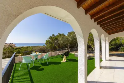an outdoor balcony with a table and chairs on the grass at Ayia Napa Ammos Sea View Villa in Ayia Napa