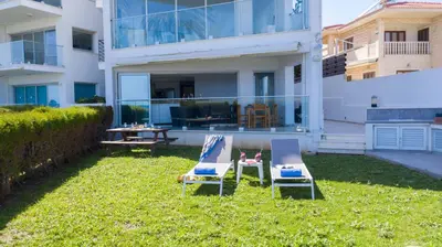 two chairs and a table in the grass in front of a building at Apartment Trident 4 in Paralimni