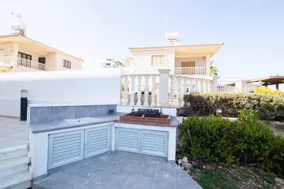 a backyard with a grill in front of a house at Apartment Trident 4 in Paralimni