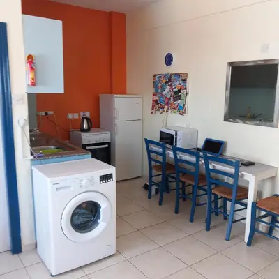 a kitchen with a washing machine and a table with chairs at Ayia Napa Sun Central in Ayia Napa