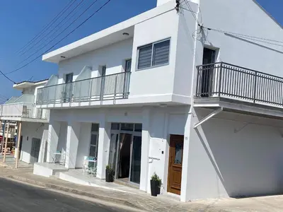 a white house with a balcony on a street at ElleNapa Apts & Studios in Ayia Napa