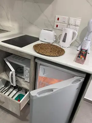 a kitchen counter with a sink and an open refrigerator at ElleNapa Apts & Studios in Ayia Napa