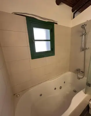 a bathroom with a bath tub and a window at Lasmari's Bouquet in Sykopetra