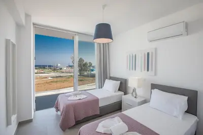 a bedroom with two beds and a large window at Villa Naya in Protaras