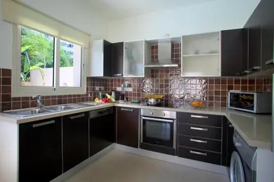 a kitchen with brown cabinets and a sink and a window at Protaras Villa Michelle 9 in Protaras