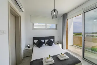 a bedroom with a bed and a large window at Protaras Villa Alasia in Protaras