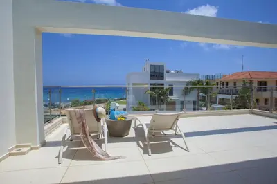 a balcony with two chairs and a view of the ocean at Central Protaras Seaview Villa Zinnia in Protaras