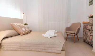 a small bedroom with a bed and a chair at Villa Katherine - Nissi Beach Area in Ayia Napa