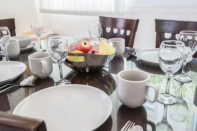 a table with a bowl of fruit and wine glasses at Protaras Villa Theodora 27 in Protaras
