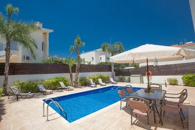 a pool with chairs and a table and an umbrella at Protaras Villa Theodora 27 in Protaras
