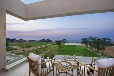 a balcony with chairs and a table and a view of the ocean at Eros Cyprus in Ayia Napa