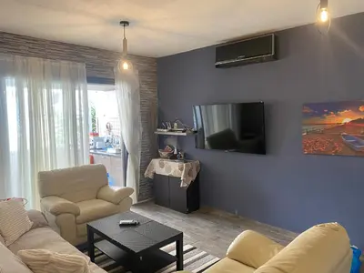 a living room with a couch and a tv on the wall at My Holiday in Ayia Napa