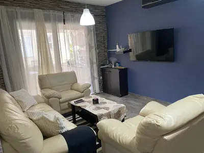a living room with two white couches and a tv at My Holiday in Ayia Napa