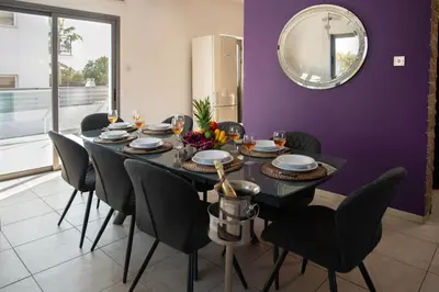 a dining room table with black chairs and a purple wall at Villa Ruby Yiasemina in Ayia Napa
