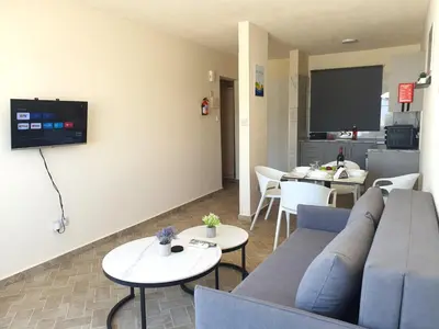 a living room with a couch and tables and a kitchen at Leucolla Hill & Sea in Protaras