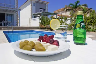 a plate of cheese and fruit on a table next to a bottle at Villa Ivory - Seafront in Ayia Napa