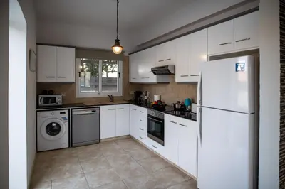 a kitchen with white cabinets and a white refrigerator at Villa Ruby Nissi Beach in Ayia Napa