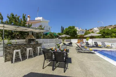 a patio with chairs and a bar next to a pool at Villa Alleli in Protaras