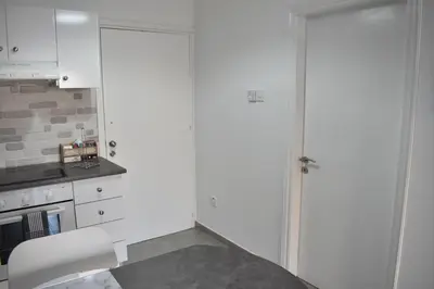 a kitchen with white cabinets and a white door at Marias Apartment - in city centre,near beach in Larnaka