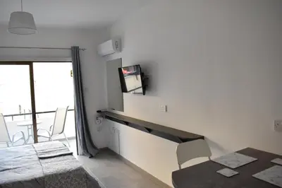 a room with a dining table and a tv on the wall at Marias Apartment - in city centre,near beach in Larnaka