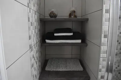 a walk in shower room with a shelf with towels at Marias Apartment - in city centre,near beach in Larnaka