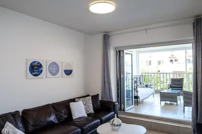 a living room with a leather couch and a balcony at Lovely 2 BR Vacation Apt Kohili Beach - 3 Min Walk in Paralimni