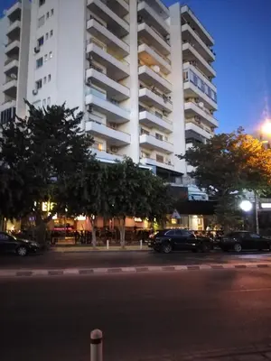 a large white building with cars parked in a parking lot at Amazing Sea Place in Limassol