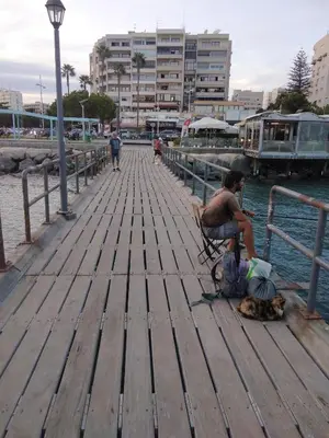 a man sitting on a wooden pier with a dog at Amazing Sea Place in Limassol