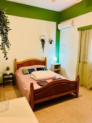 a bedroom with a bed with green and white walls at Past or Tail rooms in Larnaka