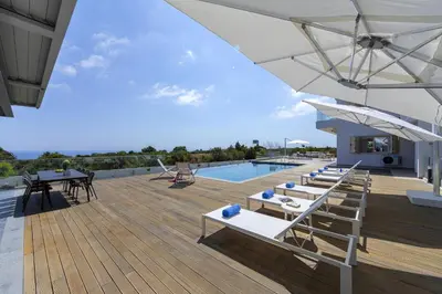 a deck with tables and chairs and a swimming pool at Villa Elite in Protaras