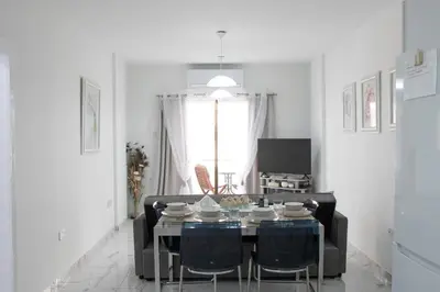 a white living room with a table and chairs at Apartment,NEAR THE BEACH Pinikoudes in Larnaka