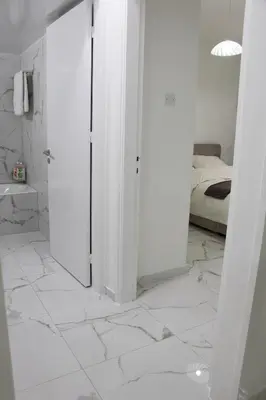 a white bathroom with a bed and a white tiled floor at Apartment,NEAR THE BEACH Pinikoudes in Larnaka