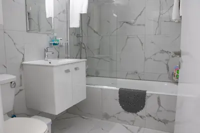 a white bathroom with a shower and a sink at Apartment,NEAR THE BEACH Pinikoudes in Larnaka