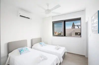 two beds in a white room with a window at Ocean 11 Villa in Protaras