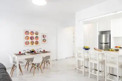 a white kitchen with white tables and chairs at Mackenzie Leo Seafront Suite in Larnaka