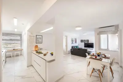 a white kitchen and living room with a couch at Mackenzie Leo Seafront Suite in Larnaka