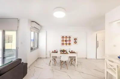 a white living room with a table and a couch at Mackenzie Leo Seafront Suite in Larnaka