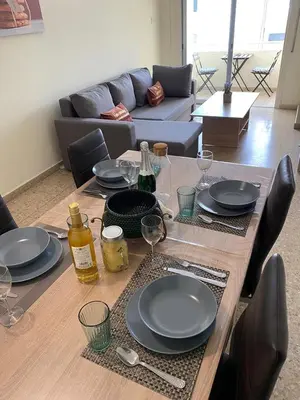 a wooden table with plates and wine glasses on it at City Comfortable Apartment in Larnaka