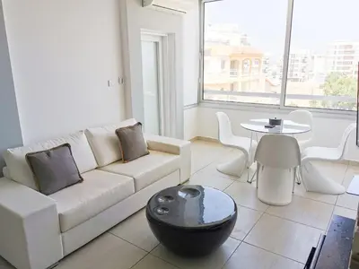 a living room with a white couch and a table at Mackenzie Seaview Paradise in Larnaka