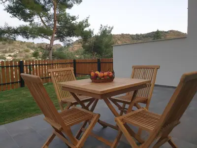 a wooden table with two chairs and a bowl of fruit at Melissonas Villas in Phini
